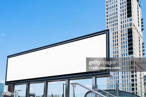 blank advertising screen against soft blue sky - billboards stockfoto's en -beelden
