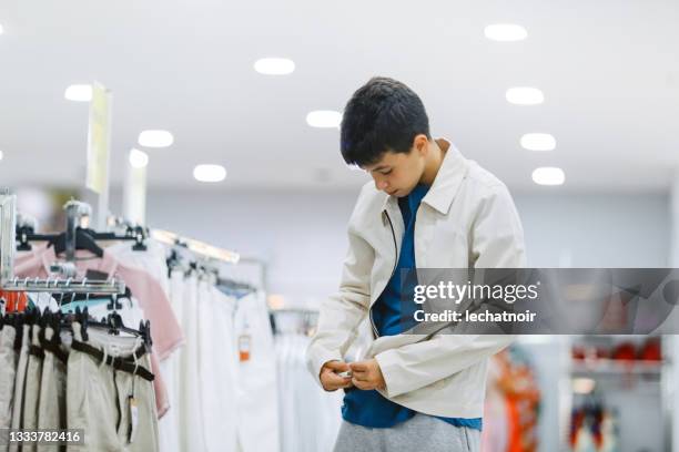 teenager boy shopping for clothes in the mall - boy clothes stockfoto's en -beelden