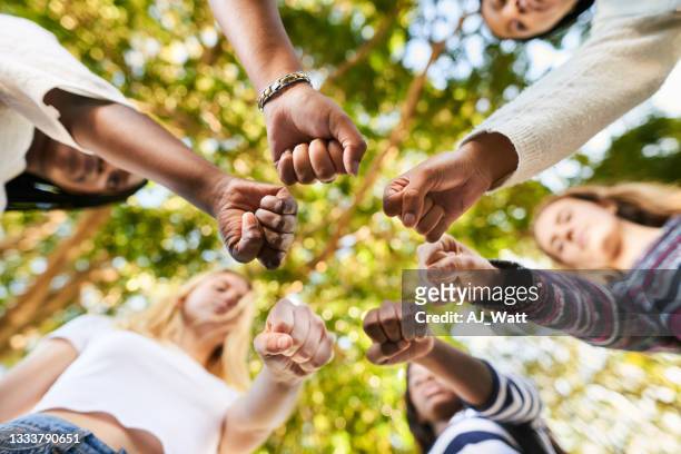 adolescentes debout avec des poings dans un cercle avant une manifestation pour l’égalité - mixed race family photos et images de collection