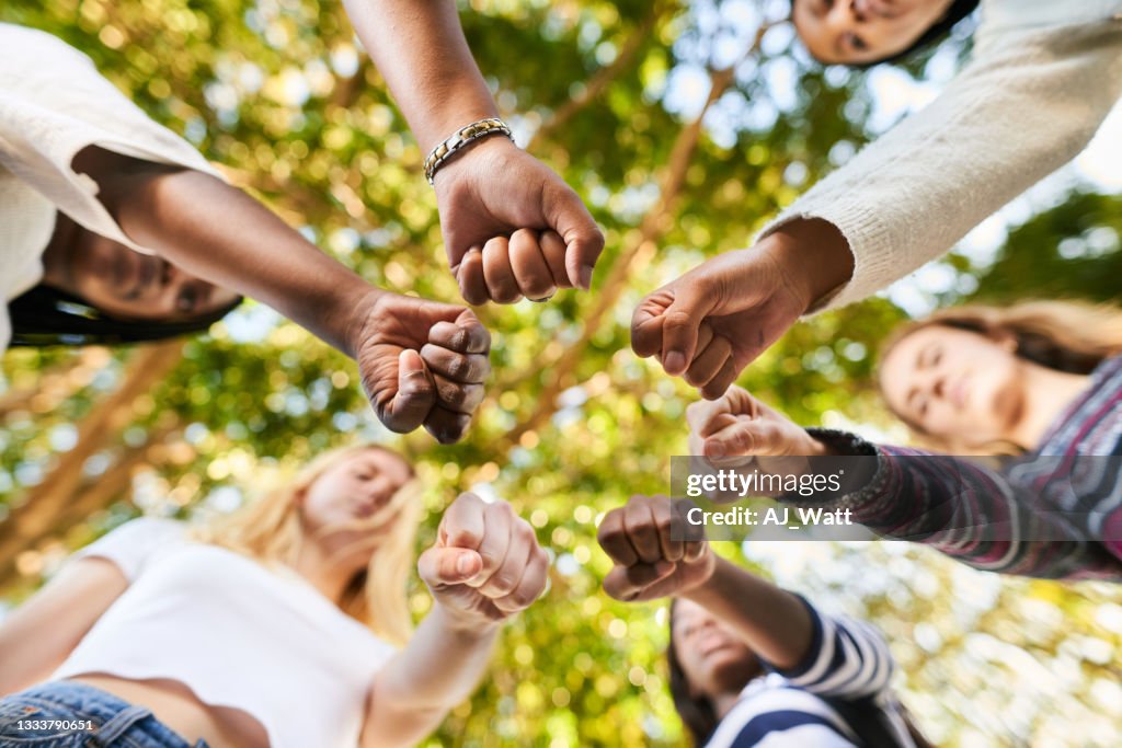 Teenage girls standing with fists in a circle before an equality protest