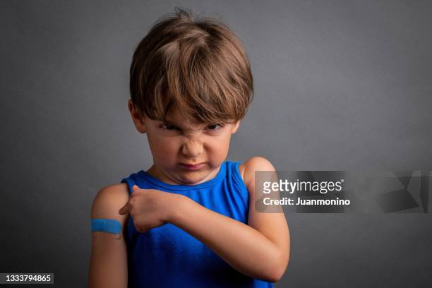 angry six years old child just after being vaccinated showing and pointing to a band aid on his arm - seven point stock pictures, royalty-free photos & images