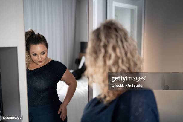 pretty woman getting dressed in front of a mirror at home - large mirror stock pictures, royalty-free photos & images