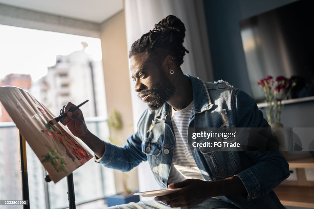 Homme peignant sur toile à la maison