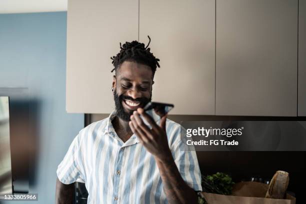 man sending audio message on smartphone at home - home audio stock pictures, royalty-free photos & images