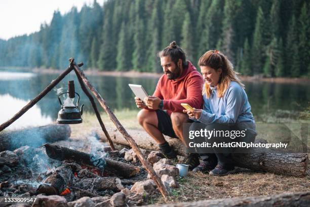 cuople joven que utiliza la tecnología en vacaciones en la naturaleza - mountian fire fotografías e imágenes de stock