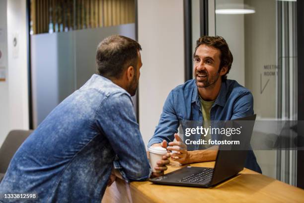 zwei männliche kollegen plaudern über die arbeit in der bürolobby - empfangraum office stock-fotos und bilder