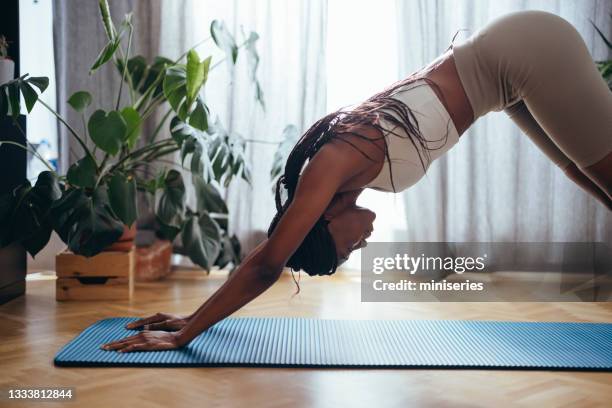 woman standing in downward facing dog pose at home - downward facing dog position stock pictures, royalty-free photos & images