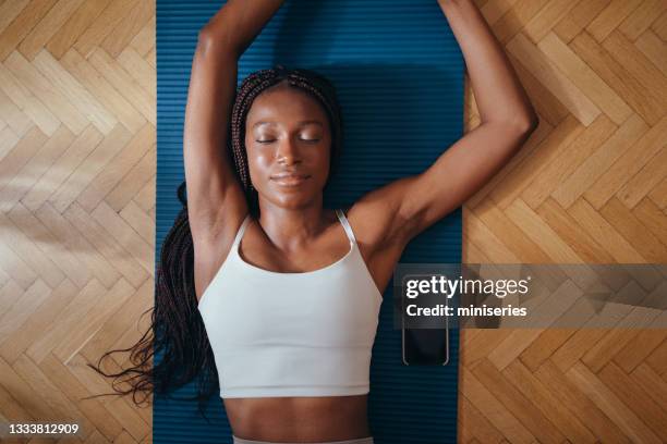 vista superior de la mujer fitness lyingâ en la estera de ejercicio azul - ropa tirada en el suelo fotografías e imágenes de stock