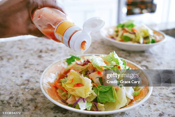 woman pours salad dressing onto salad - dressing room stock-fotos und bilder