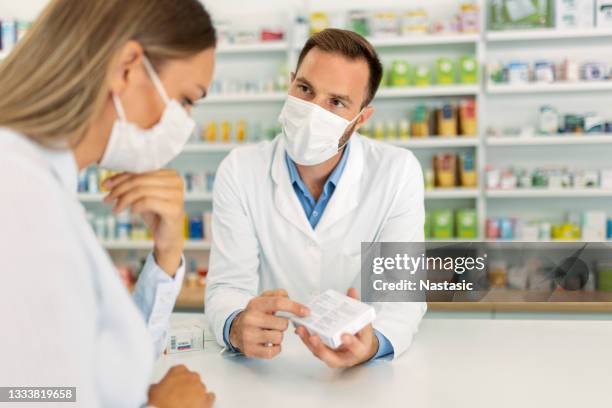 pharmacist wearing protective face mask pointing to drug - pharmacy mask stock pictures, royalty-free photos & images