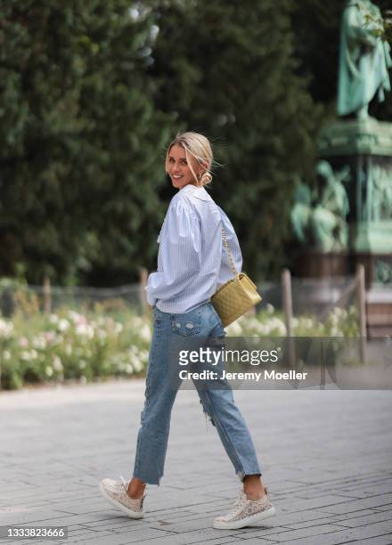 Scarlett Gartmann wearing Miu Miu blue blouse, Bdg destroyed blue jeans, Chanel yellow leather bag and Chloe beige sneaker on August 07, 2021 in...
