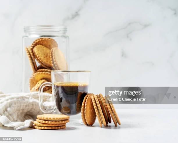 cup of coffee with sandwich cookies on white background - snack break stock pictures, royalty-free photos & images