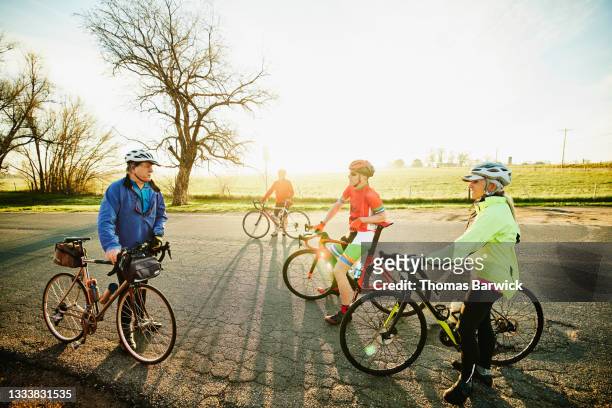wide shot of group of senior cyclists preparing for sunrise ride on spring morning - bicycle safety light stockfoto's en -beelden
