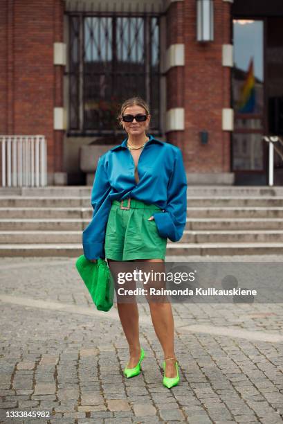 Janka Polliani wearing green shorts, blue shirt, green bag and lime green shoes outside MKDT during Copenhagen fashion week SS22 on August 12, 2021...