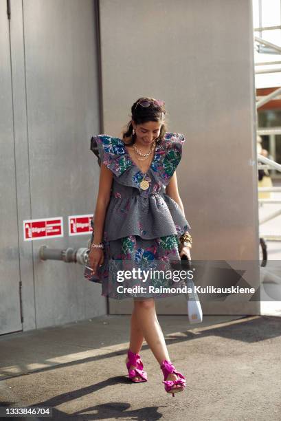 Guest wearing Ganni colorful dress with pink shoes outside Ganni during Copenhagen fashion week SS22 on August 12, 2021 in Copenhagen, Denmark.