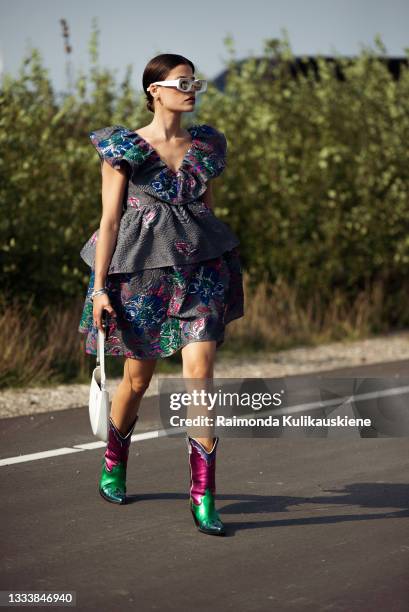 Guest wearing Ganni dress and cowboy boots outside Ganni during Copenhagen fashion week SS22 on August 12, 2021 in Copenhagen, Denmark.