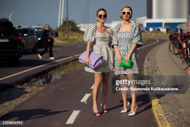 Karolina Wojcik wearing checked dress and purple bag and Justyna Czerniak wearing a dress and a green bag outside Ganni during Copenhagen fashion...