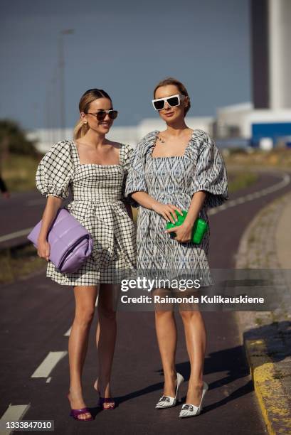 Karolina Wojcik wearing checked dress and purple bag and Justyna Czerniak wearing a dress and a green bag outside Ganni during Copenhagen fashion...