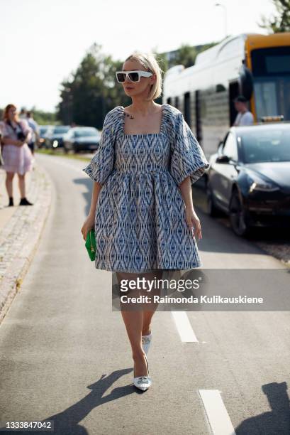 Justyna Czerniak wearing dress and green bag outside Ganni during Copenhagen fashion week SS22 on August 12, 2021 in Copenhagen, Denmark.