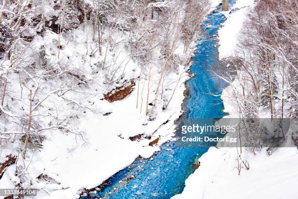 biei river stream  in winter at shirogane blue pond, biei, hokkaido, japan - kamikawa hokkaido stock-fotos und bilder