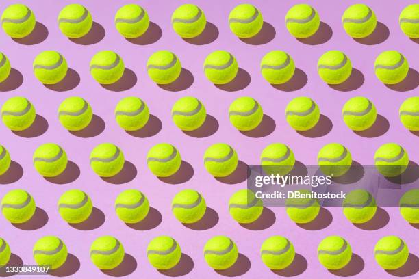 yellow tennis balls pattern on pink background with hard shadows. sport and tennis concept - tennisbal stock-fotos und bilder