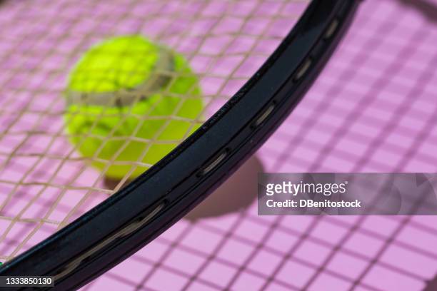 yellow tennis ball with unfocused hard shadow, under the string of a racket on pink background - abstract tennis player stock pictures, royalty-free photos & images