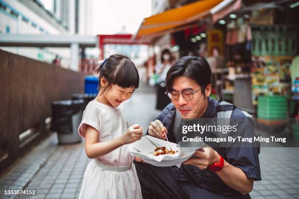 dad & daughter enjoying hong kong local street food joyfully in street - hong kong family stockfoto's en -beelden