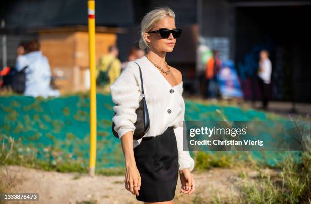 Caroline Caro Daur seen wearing black skirt, white cardigan, black boots, bag outside Ganni on August 12, 2021 in Copenhagen, Denmark.