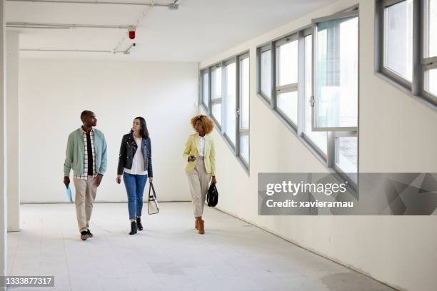 real estate agent and clients touring shell condition office space - commercial real estate agent stock pictures, royalty-free photos & images