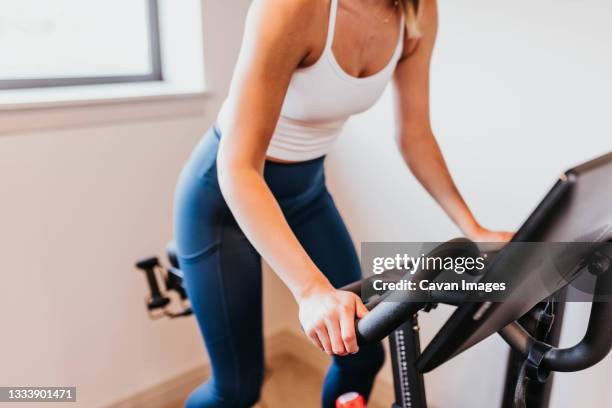 close up of woman riding exercise bike in home gym - peloton ストックフォトと画像