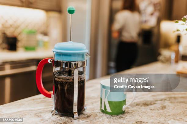 close up of french press full of coffee next to mug - coffee plunger stock-fotos und bilder