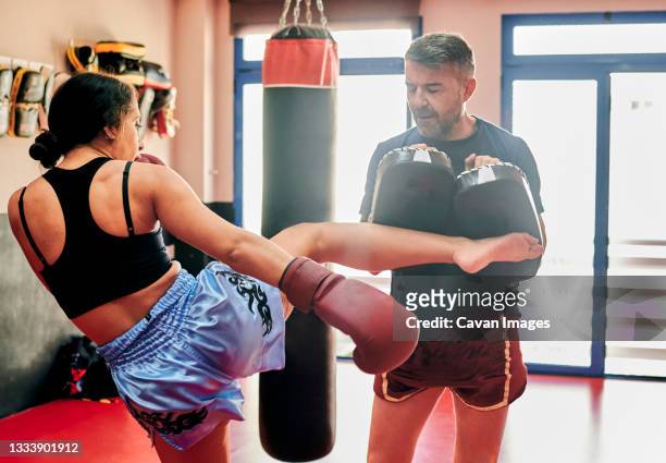 young woman training with her muay thai trainer in a gym - defensa propia fotografías e imágenes de stock