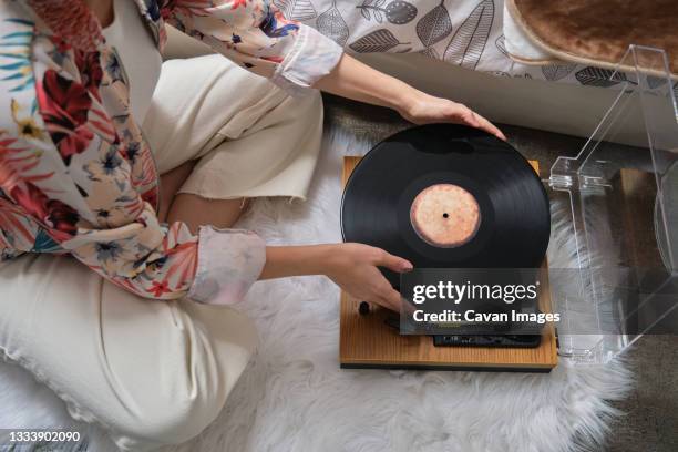 unrecognizable woman putting on a vinyl record on a turntable - tocadiscos fotografías e imágenes de stock