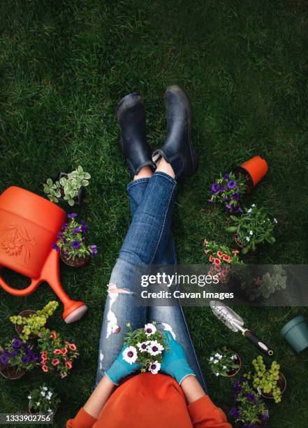 overhead of woman on grass surrounded by plants and gardening tools. - boots over pants stock pictures, royalty-free photos & images