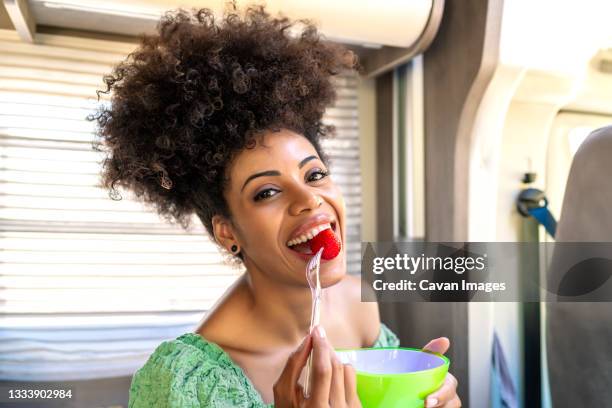 pretty african woman eating a healthy strawberry - cultura afro americana stock-fotos und bilder