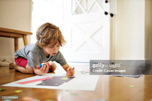 boy holding glue while making paper art at home - sticky stock pictures, royalty-free photos & images