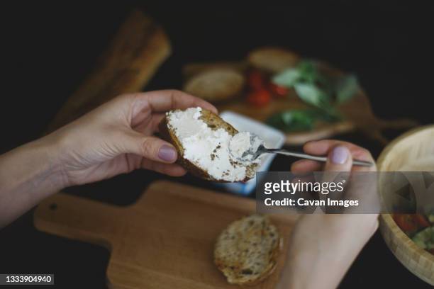 close up of woman spreads curd cheese on a slice of bread - sparse foto e immagini stock