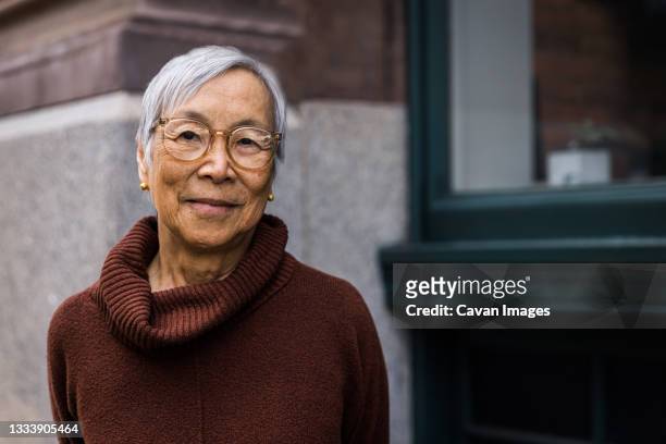 portrait of smiling senior woman wearing glasses in the city - chinese people posing for camera stock pictures, royalty-free photos & images