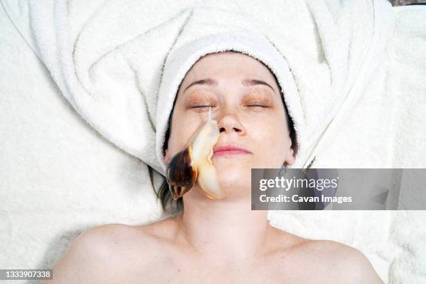a 40-year-old woman rejuvenates her face with a snail - weinbergschnecke stock-fotos und bilder