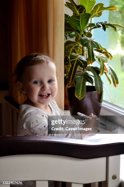 smiling little girl looking at camera while standing in bed - toodler fotografías e imágenes de stock