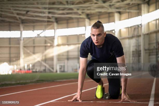 determined male runner in crouch start position on track - sprint photos et images de collection