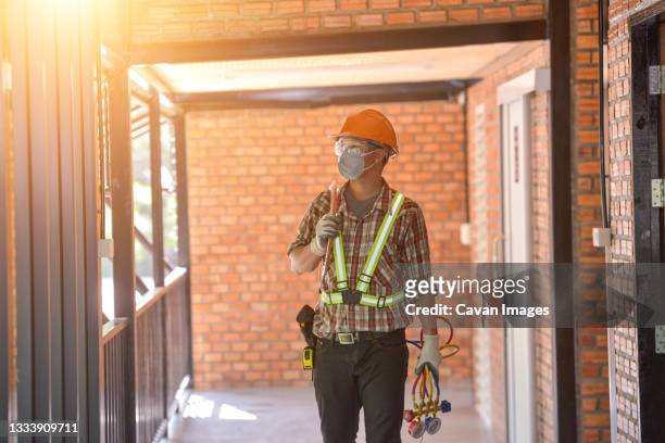 air conditioner repairmen work on home unit. - air cooler stock pictures, royalty-free photos & images