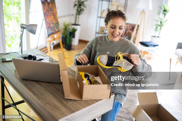 giovane donna che spacchetta stivali da scatola di cartone che ha ricevuto dopo lo shopping online - calzature foto e immagini stock