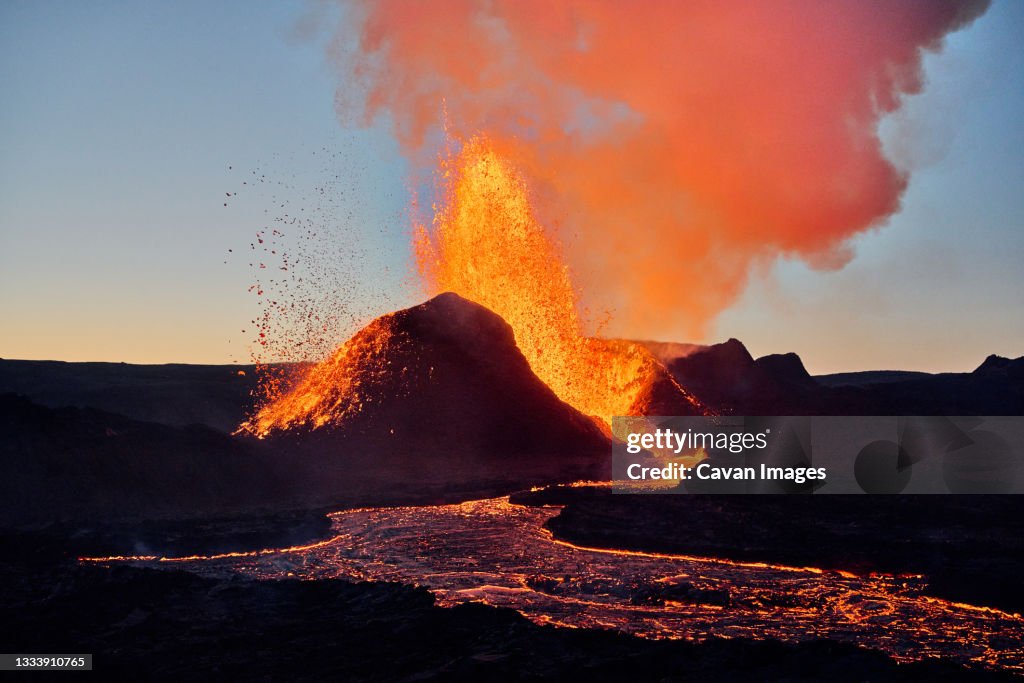 Hot lava erupting from volcano at sunset