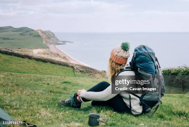 woman hiking the jurassic coast in england having a cup of tea camping - dorset engeland stockfoto's en -beelden