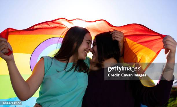 beautiful lesbian couple having fun in the street with a lgtb flag - teenage lesbian fotografías e imágenes de stock