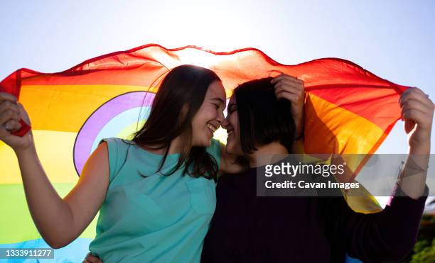 beautiful lesbian couple having fun in the street with a lgtb flag - teen lesbians stock pictures, royalty-free photos & images