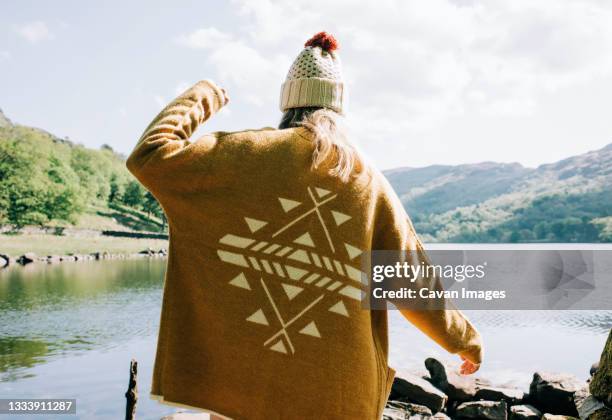 woman wearing aztec cardigan walking by the lake and mountains - aztec print stock pictures, royalty-free photos & images