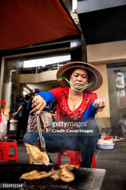 vendor cooks fish filets for locals and tourists wanting street food - vietnamese street food stock pictures, royalty-free photos & images