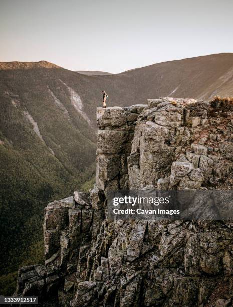 male trail runner stands at edge of cliff on bondcliff, new hampshire - valley side stock-fotos und bilder